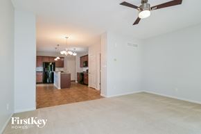 Saint Charles house for rent - A spacious room with a ceiling fan and a view of a kitchen in the background.