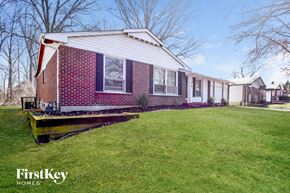 Florissant house for rent - A red brick house with a white roof and a green lawn in front.