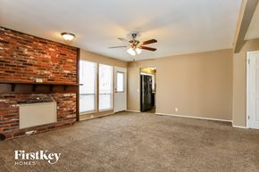 Florissant house for rent - A spacious room with a brick fireplace and a ceiling fan.