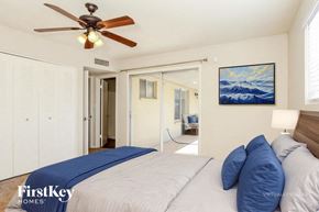 Phoenix house for rent - A bedroom with a bed, a ceiling fan, and a painting of a mountain scene on the wall.