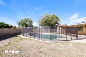 Phoenix house for rent - A pool enclosed by a fence with trees in the background.