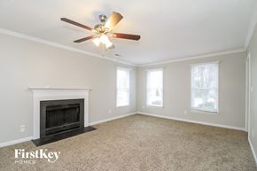 High Point house for rent - A spacious room with a fireplace and a ceiling fan.