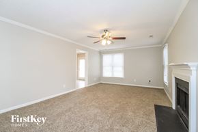 High Point house for rent - A spacious room with a fireplace and a ceiling fan.
