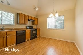 Fort Worth house for rent - an empty kitchen with wood flooring and black appliances