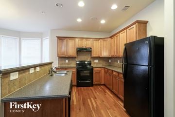 Cumming house for rent - a kitchen with wooden cabinets and a black refrigerator