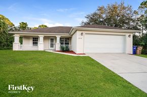 Lehigh Acres house for rent - a white house with a driveway and a lawn