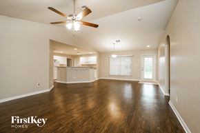 Lehigh Acres house for rent - an empty living room with a ceiling fan and a kitchen