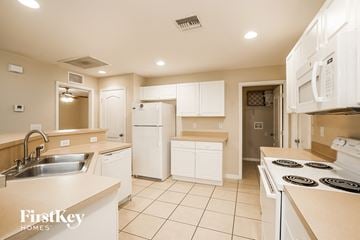 Lehigh Acres house for rent - a kitchen with white cabinets and appliances and a sink