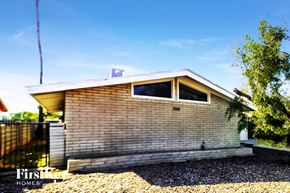 Tempe house for rent - A house with a brown brick exterior and a gravel driveway in front.