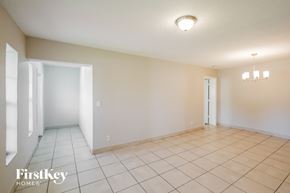 Miami Gardens house for rent - A spacious room with a tile floor and a chandelier hanging from the ceiling.