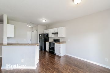 North Port house for rent - a kitchen with white cabinets and a black stove and refrigerator