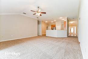 Orange Park house for rent - an empty living room with a ceiling fan and a kitchen