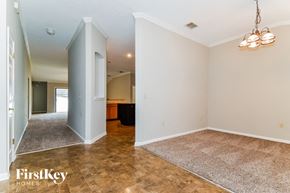 Orange Park house for rent - an empty living room and dining room with white walls and wood flooring