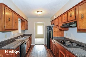 Memphis house for rent - a kitchen with wood cabinets and black appliances and granite counter tops