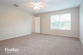 Dallas house for rent - A room with a carpet floor, a ceiling fan, and a window with a view of trees.