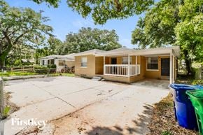 Tampa house for rent - a small yellow house with a driveway and a yard with trees