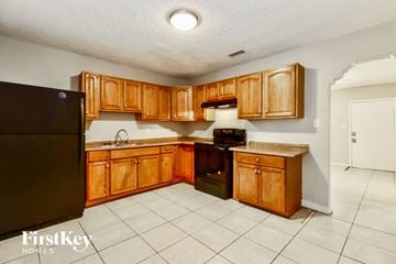 Tampa house for rent - a kitchen with wooden cabinets and a black refrigerator
