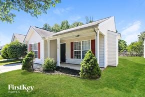 Charlotte house for rent - A white house with red shutters and a black door is surrounded by greenery.