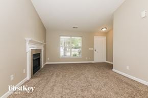 Charlotte house for rent - A spacious room with a fireplace and carpeted floor.