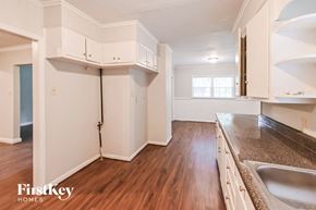Memphis house for rent - an empty kitchen with white cabinets and a wood floor