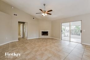 Winter Haven house for rent - an empty living room with a fireplace and a ceiling fan