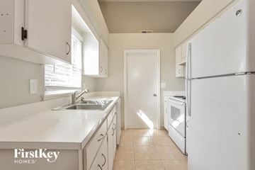 Winter Haven house for rent - a kitchen with white cabinets and a sink and a refrigerator