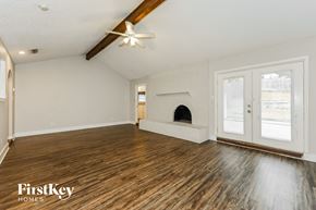 North Richland Hills house for rent - A spacious room with wooden floors and a fireplace.