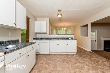 Decatur house for rent - a kitchen with white cabinets and granite counter tops