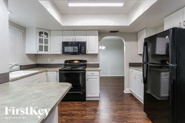 Cape Coral house for rent - A kitchen with a black refrigerator and white cabinets.