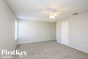 Dallas house for rent - the spacious living room with carpeting and a ceiling fan