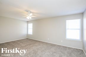 Dallas house for rent - a bedroom with carpet and a ceiling fan and two windows