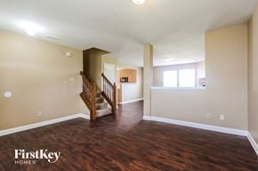 Indianapolis house for rent - A spacious room with wooden floors and a staircase leading to another room.