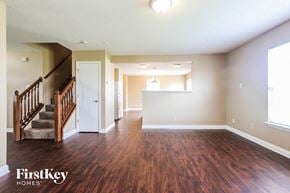 Indianapolis house for rent - A spacious room with wooden floors and a staircase leading to another room.