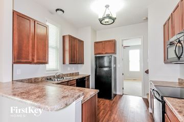Saint Charles house for rent - A kitchen with brown cabinets and a black refrigerator.