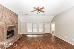 Bartlett house for rent - A spacious room with a brick fireplace and a ceiling fan.
