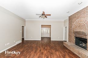 Bartlett house for rent - A spacious living room with a brick fireplace and a ceiling fan.