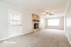 Conyers house for rent - A spacious room with a fireplace and a ceiling fan.
