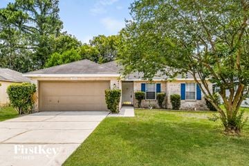 Jacksonville house for rent - a home with a garage door and a lawn and trees