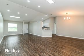 Lehigh Acres house for rent - A spacious room with wooden flooring and a kitchenette in the background.