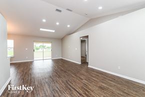 Lehigh Acres house for rent - A spacious room with wooden floors and a slanted ceiling.