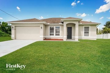 Cape Coral house for rent - a beige house with a lawn in front of it