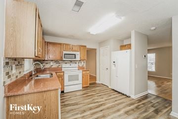 Charlotte house for rent - a kitchen with wooden cabinets and a white refrigerator