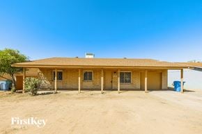 Phoenix house for rent - the front of a brick house with a dirt lot and a garage