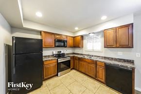Phoenix house for rent - a kitchen with wooden cabinets and black appliances and tiled floors