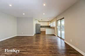Plano house for rent - A spacious room with wooden floors and a kitchen area in the background.