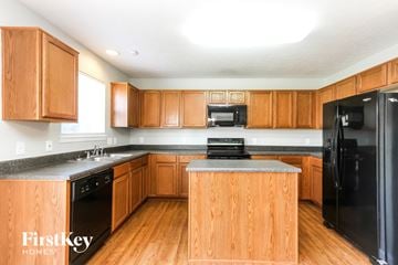 Indianapolis house for rent - A kitchen with wooden cabinets and a black fridge.