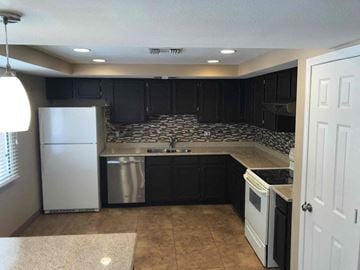 Phoenix house for rent - a kitchen with black cabinets and a white refrigerator
