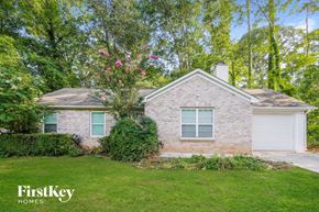 Gainesville house for rent - a small brick house with a lawn and a white garage