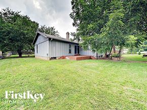 Florissant house for rent - the front of a white house with a yard and trees
