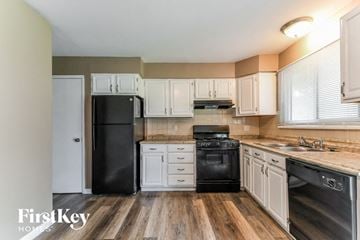 Florissant house for rent - a kitchen with white cabinets and black appliances